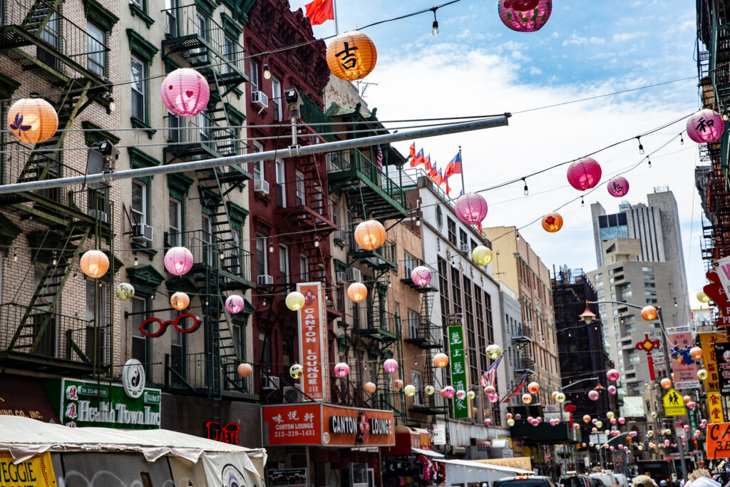 Street scene in Chinatown NYC, with colorful paper lanterns strung up between buildings.