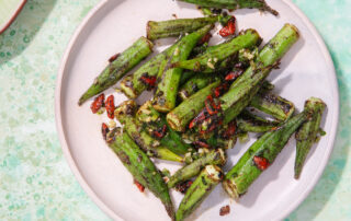 Dry-fried okra on a round plate. The background is a mottled, pale green surface.