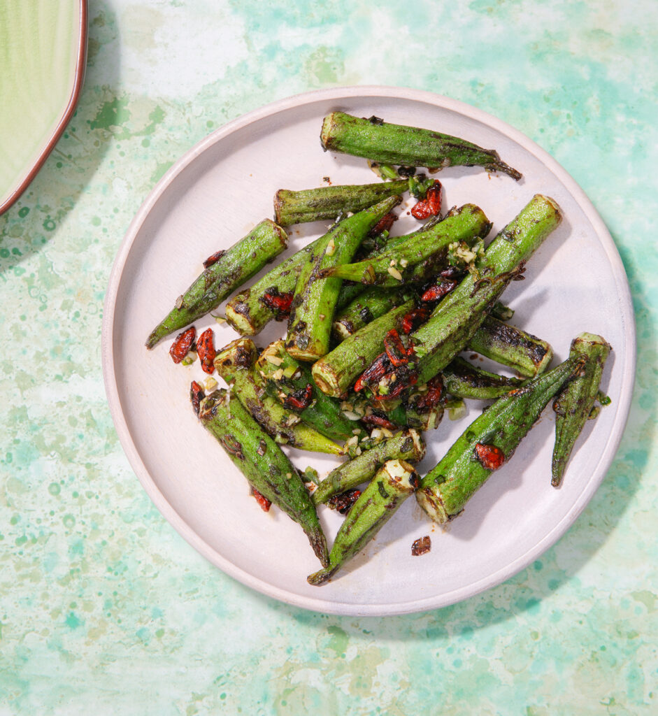 Dry-fried okra on a round plate. The background is a mottled, pale green surface.